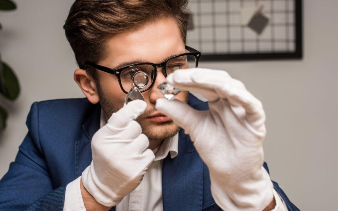 Close-up of a jewelry appraiser with glasses and white gloves inspecting a gemstone with a magnifying glass, focusing on precision and detail.