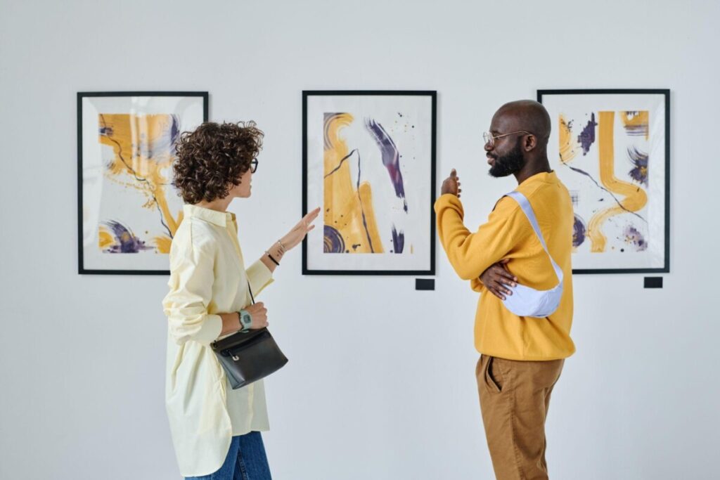 Two potential buyers discussing artwork at a gallery, evaluating a private sale purchase. A direct, controlled selling approach ideal for those looking to sell artwork privately.